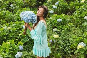 joven y hermosa mujer florista recogiendo flores de hortensia foto