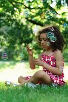 Black little girl blowing a soap bubbles in a city park