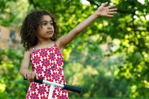 niña negra con una patineta en un parque de la ciudad foto