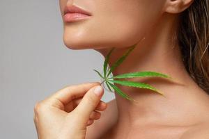 CBD cosmetics concept. Beautiful woman with a cannabis leaf photo