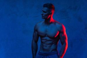 Muscular man posing in the colorful light photo