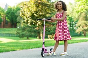 niña negra con una patineta en un parque de la ciudad foto