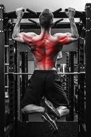 espalda especialización en musculación. hombre haciendo pull-ups en una barra horizontal foto