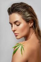 CBD cosmetics concept. Beautiful woman with a cannabis leaf photo