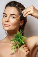 CBD cosmetics concept. Beautiful woman with a cannabis leaf photo