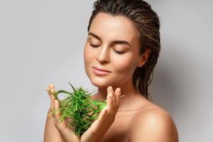 CBD cosmetics concept. Beautiful woman with a cannabis leaf photo