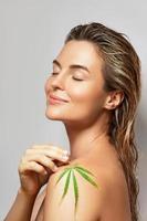 CBD cosmetics concept. Beautiful woman with a cannabis leaf photo