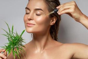 CBD cosmetics concept. Beautiful woman with a cannabis leaf photo