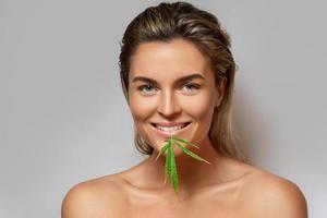 CBD cosmetics concept. Beautiful woman with a cannabis leaf photo