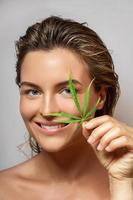 CBD cosmetics concept. Beautiful woman with a cannabis leaf photo