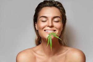 CBD cosmetics concept. Beautiful woman with a cannabis leaf photo