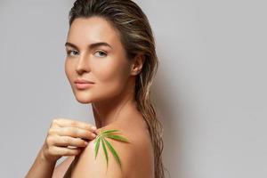 CBD cosmetics concept. Beautiful woman with a cannabis leaf photo