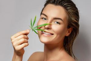 CBD cosmetics concept. Beautiful woman with a cannabis leaf photo