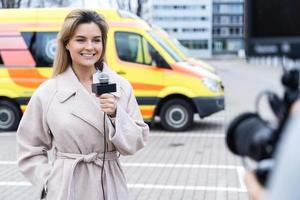 reportero de noticias sonriente hablando en un micrófono foto