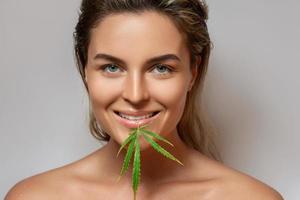 CBD cosmetics concept. Beautiful woman with a cannabis leaf photo