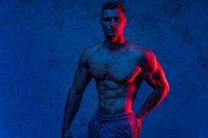 Muscular man posing in the colorful light photo
