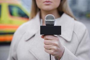 Journalist speaking into the microphone beside the ambulance vehicle photo