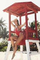 Sexy woman in red swimsuit beside lifeguard tower on the beach photo