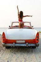 Sexy woman wearing red swimsuit is sitting inside a retro cabriolet car photo