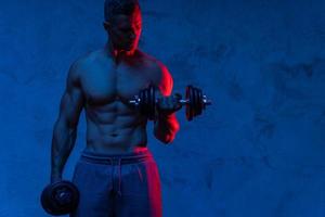 Young and muscular man working out with dumbbells photo
