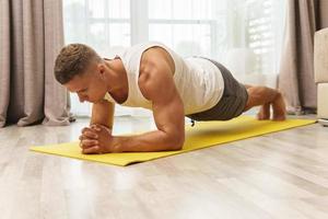 hombre haciendo tablones durante un intenso entrenamiento en casa foto