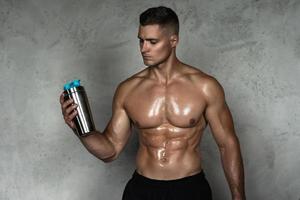 hombre musculoso bebiendo proteína de suero u otro suplemento deportivo foto