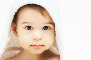 Cute infant boy with beautiful eyes wrapped into hooded towel after a bathing photo