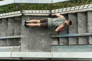 Muscular man is doing push-ups during calisthenic workout on a street photo