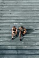 pareja atlética sentada en una escalera de hormigón después de trotar o hacer ejercicio al aire libre foto