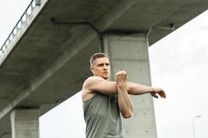 Muscular man warming up before his outdoor fitness workout photo