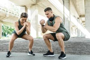 Athletic couple doing squats during street workout photo