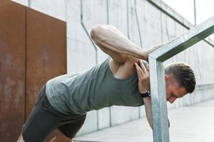 Handsome muscular man doing one arm push-up photo