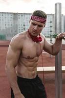 Muscular man wearing red bandana during his calisthenics workout on the street photo