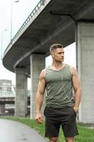 Handsome man with an earphones. Listening music during a fitness workout on a street. photo