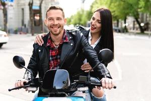 Stylish couple having fun while riding electric scooter on city street photo