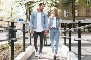 pareja amorosa vistiendo trajes de mezclilla caminando durante su cita en una calle de la ciudad foto