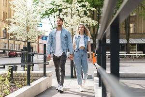 pareja amorosa vistiendo trajes de mezclilla caminando durante su cita en una calle de la ciudad foto