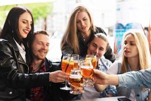 amigos celebrando y sosteniendo vasos con diferentes bebidas alcohólicas en un bar. foto