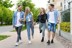 Group of best friends are having fun while walking by city street photo