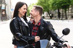 Stylish couple having fun while riding electric scooter on city street photo