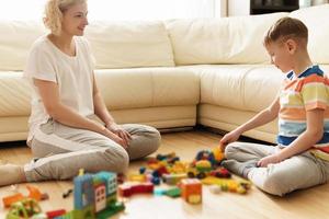 Cute boy and his mother playing together at home photo