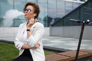 Young businesswoman smoking vape after her work photo