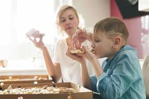 Mother and her cute son eating delicious pizza at home photo