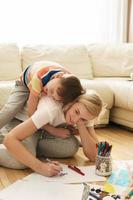 Happy mother and son are drawing together at home photo