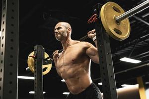 Bodybuilder during his workout with a barbell in the gym photo