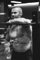 Bearded bodybuilder during his workout with a barbell in the gym photo