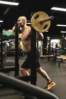 Bodybuilder during his workout with a barbell in the gym photo
