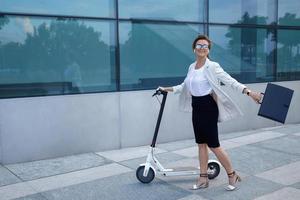 Young and beautiful businesswoman rides electric scooter photo