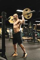 Bodybuilder during his workout with a barbell in the gym photo