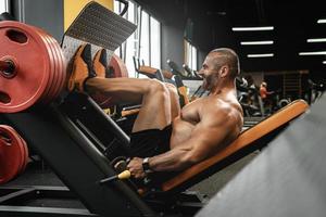 Bodybuilder doing a seated leg press exercise in a gym photo